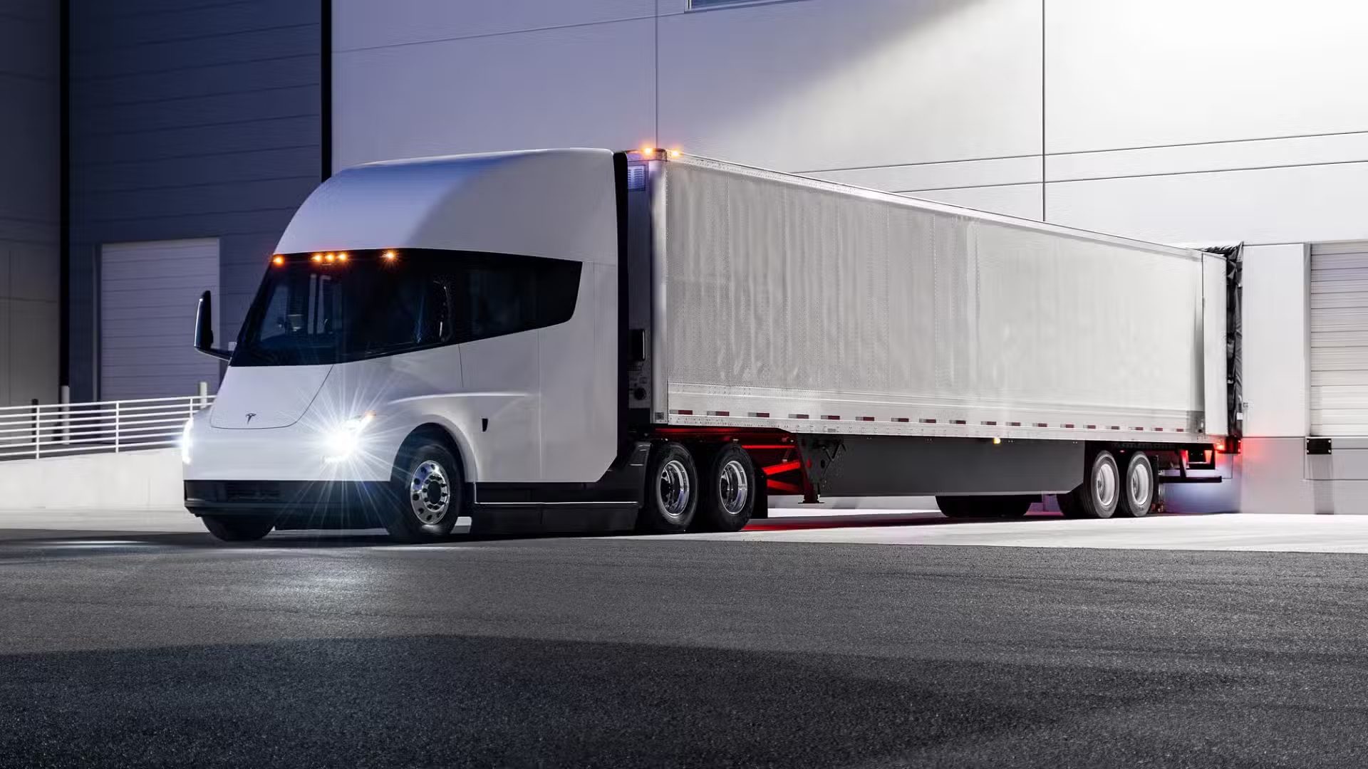 Three-quarter side view of a Tesla semi truck loading at warehouse