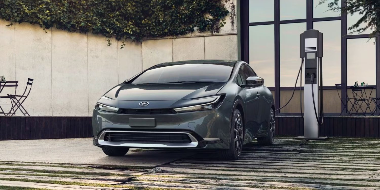 Three-quarter front view of a gray Toyota Prius Prime charging at home.