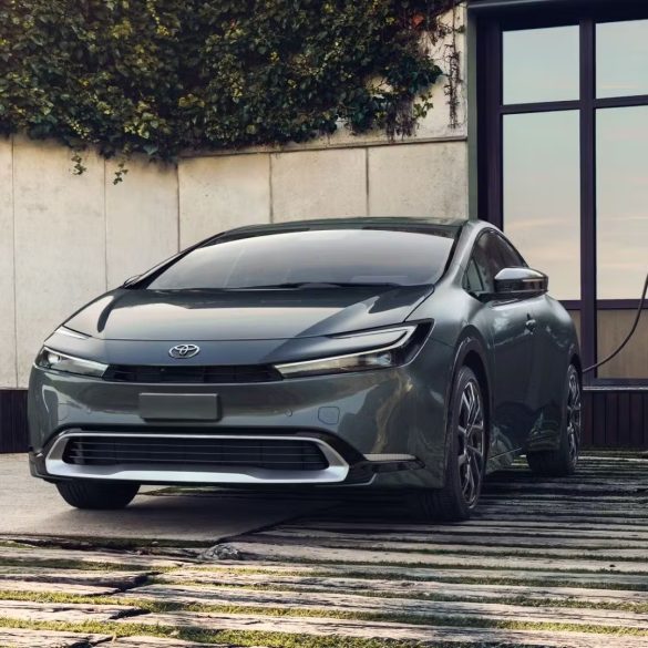 Three-quarter front view of a gray Toyota Prius Prime charging at home.