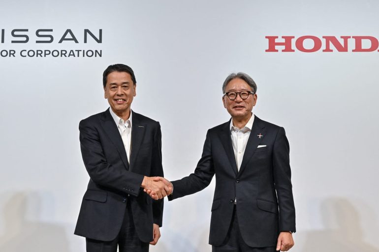 Nissan CEO Makoto Ushida and Honda CEO Toshihiro Mibe shaking hands