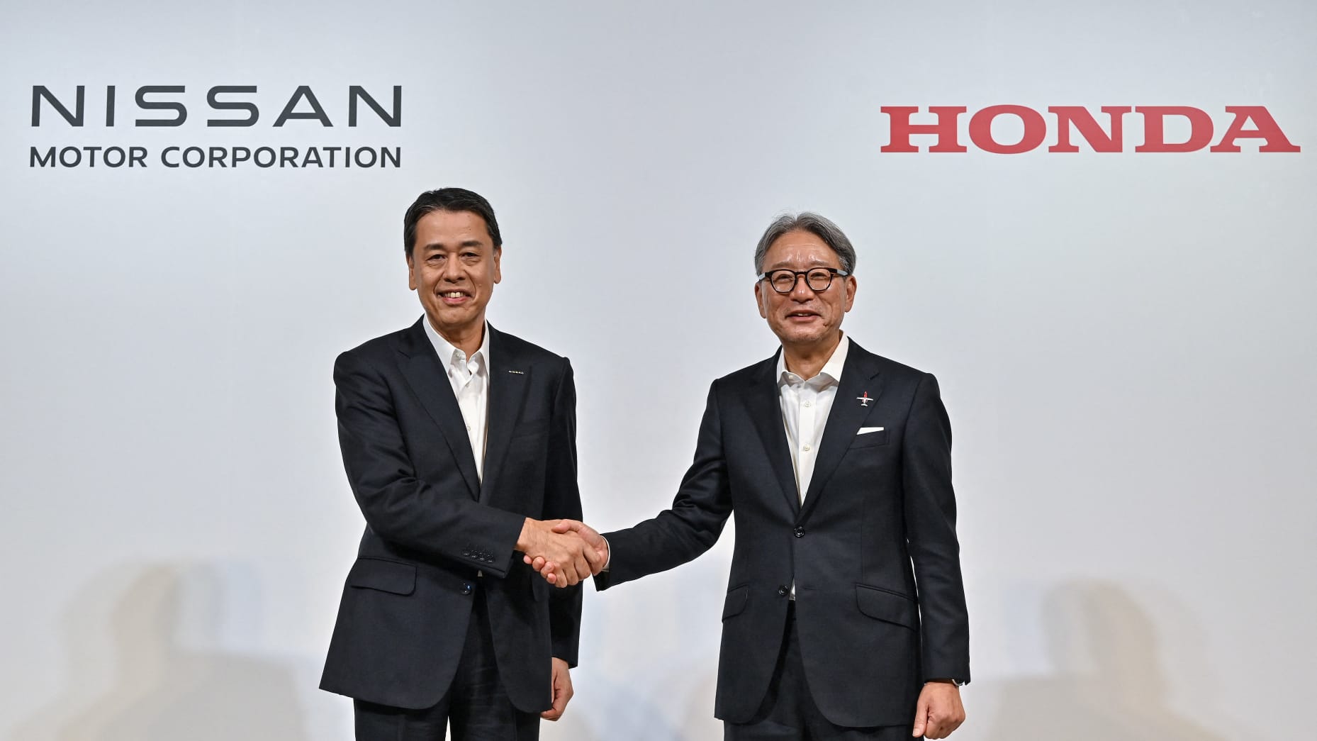 Nissan CEO Makoto Ushida and Honda CEO Toshihiro Mibe shaking hands